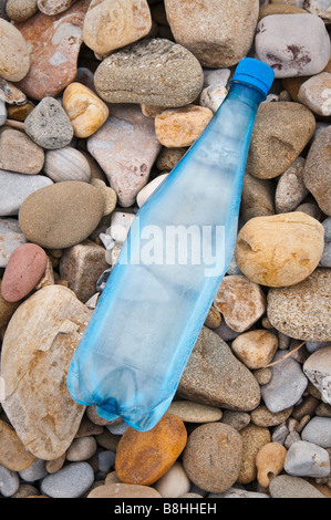 Une vieille bouteille d'eau bleu échoué sur une plage de galets Banque D'Images