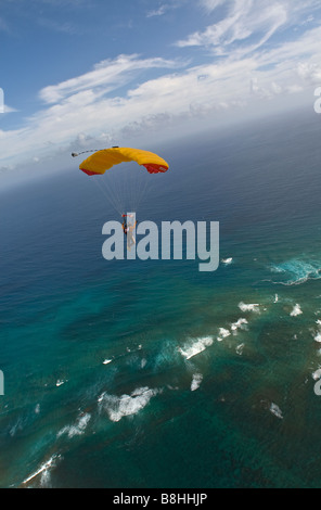 Parachutiste sous l'auvent est volant le long de la ligne de coût à partir d'Hawaï se prépare à faire une plage de l'atterrissage. Banque D'Images