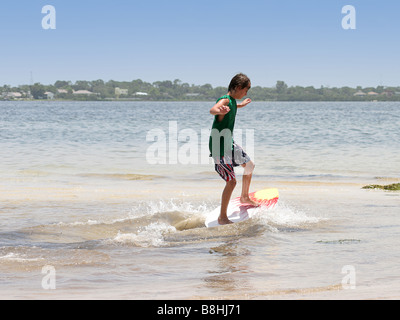 Garçon à la plage d'embarquement écrémé Banque D'Images