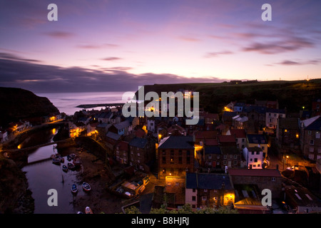 Une vue de staithes à l'aube avec le village lights glowing sous un soleil rose prises depuis les falaises au-dessus Banque D'Images