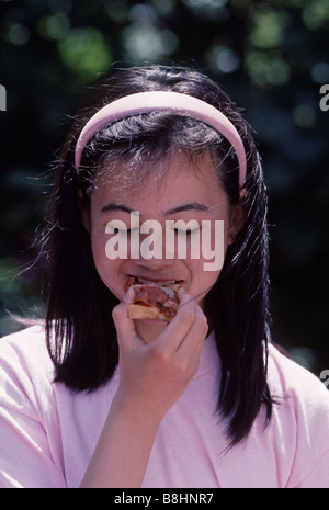 Treize ans, fille mange une tranche de pizza à San Francisco California USA Banque D'Images