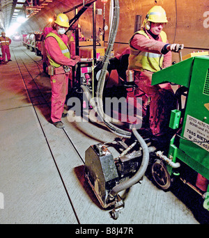 Les rainures de coupe dans un sol en béton du Tunnel sous la Manche tunnel de service avant d'installer les fils d'orientation pour les véhicules STTS. Banque D'Images