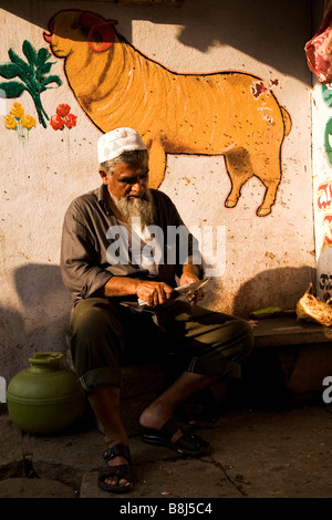 Un boucher signifie des coupes à partir d'un os sur la rue à Bangalore, Inde. Banque D'Images