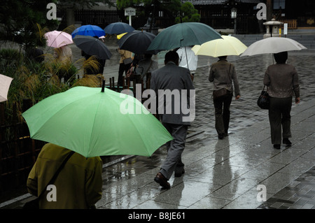 Les pèlerins arrivant à Tokyo's Sengaku-ji avec parasols colorés dans la pluie Banque D'Images