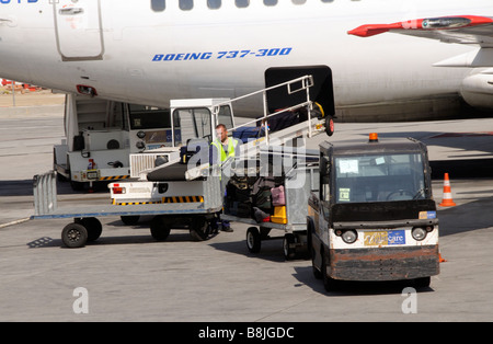 Bagagiste décharger les bagages d'un Boeing 737 avion à réaction à l'Aéroport International de Malaga au sud de l'Espagne Banque D'Images