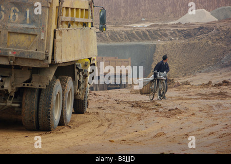 Un travailleur chinois recueille des vêtements des autres travailleurs d'être blanchi dans un vaste projet d'excavation. Banque D'Images