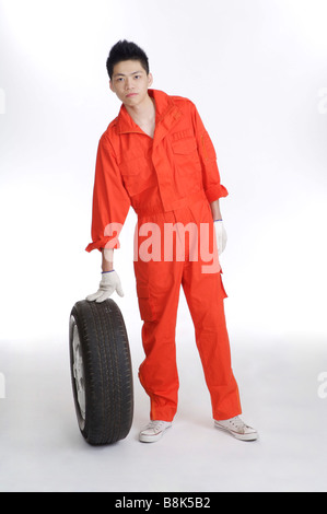 Jeune travailleur ayant un pneu et regardant la caméra Banque D'Images