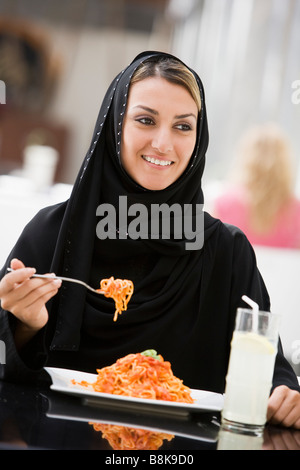 Femme au restaurant mange du spaghetti et smiling (selective focus) Banque D'Images