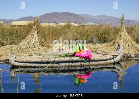 Uros femme indienne en tortora reed alimentation bateau cobayes (cuy) élevés pour l'alimentation, le Lac Titicaca, Pérou Banque D'Images