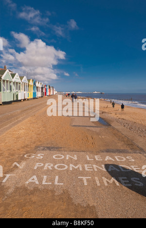 Les gens qui marchent le long de la promenade de la plage de Southwold sur une belle journée avec les chiens sur avis mène à l'avant-plan Banque D'Images