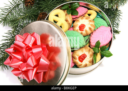 Une boîte de délicieux biscuits des fêtes colorées niché sous l'arbre de Noël fond blanc Banque D'Images