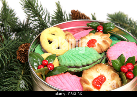 Une boîte de biscuits des fêtes colorées niché sous l'arbre de Noël fond blanc Banque D'Images