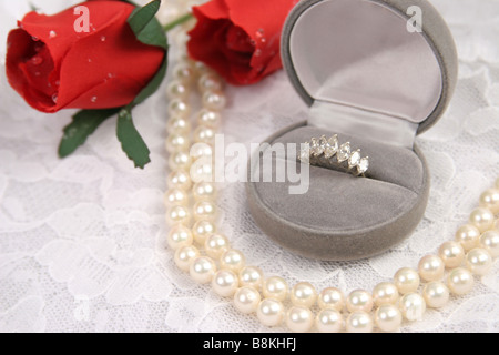 Un anneau de diamant collier de perles et de roses sur un fond de dentelle Banque D'Images