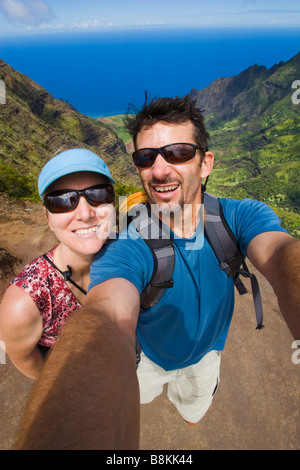 Couple d'âge moyen de prendre une photo numérique d'eux-mêmes à partir d'une vue surplombant Kalalau Valley sur la côte de Na Pali Banque D'Images