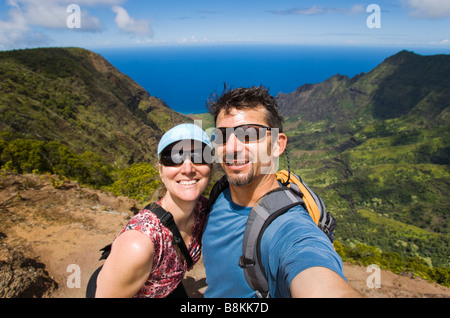 Couple d'âge moyen de prendre une photo numérique d'eux-mêmes à partir d'une vue surplombant Kalalau Valley Banque D'Images