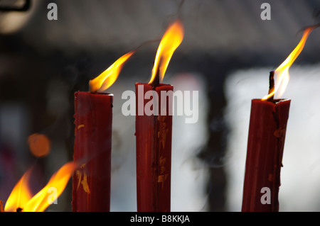 Les bougies sont la gravure et l'incendie s'allume pour des moines et d'autres personnes prennent part à une prière offre en un temple bouddhiste chinois. Banque D'Images