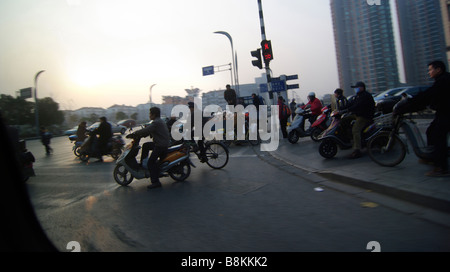 Une foule de personnes qui conduisent les cyclomoteurs et scooters et bicyclettes, équitation, course sur une rue animée à l'heure de pointe en Chine. Banque D'Images