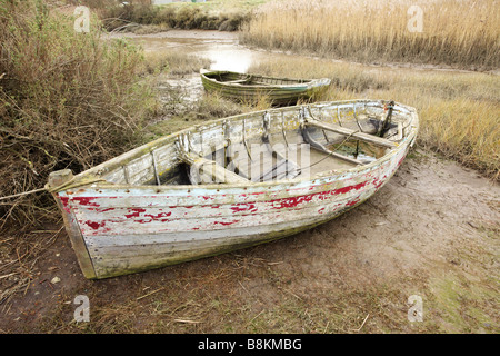 Vieux bateaux inutilisés se trouvant à marée basse, les marais salants de la côte nord du comté de Norfolk [Royaume-Uni]. Banque D'Images