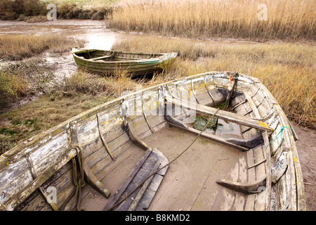 Vieux bateaux inutilisés se trouvant à marée basse, les marais salants de la côte nord du comté de Norfolk [Royaume-Uni]. Banque D'Images