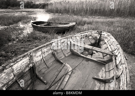 Vieux bateaux inutilisés se trouvant à marée basse, les marais salants de la côte nord du comté de Norfolk [Royaume-Uni]. Banque D'Images