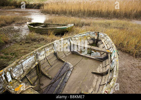 Vieux bateaux inutilisés se trouvant à marée basse, les marais salants de la côte nord du comté de Norfolk [Royaume-Uni]. Banque D'Images