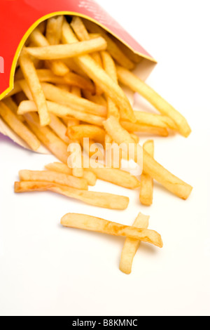 Fast food malsaine. Frites tombant de carton fort incliné, deux pièces qui ressemble à une croix, fond blanc Banque D'Images