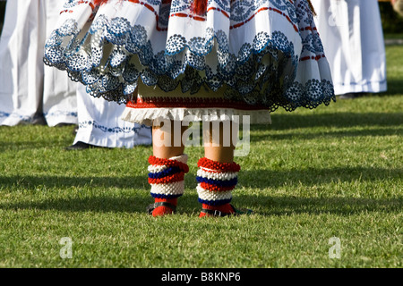 Fille dans la robe traditionnelle croate mettant ses chaussettes à cause de la chaleur Banque D'Images