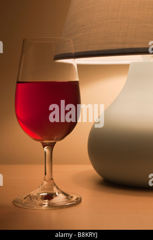 Verre de vin rouge avec une lampe de table dans la soirée. Concept simple. England UK Banque D'Images