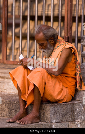 L'Inde Tamil Nadu Tiruvannamalai temple Arunachaleswar homme vêtu de safran la lecture des Écritures Banque D'Images