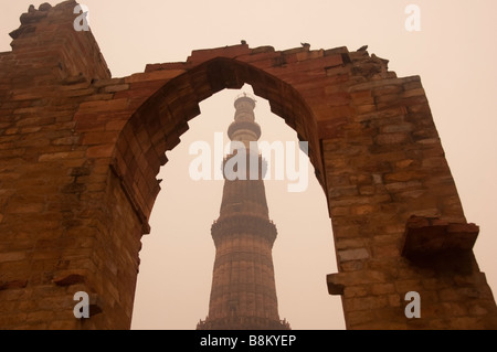 Section transversale du Qutub Minar encadrée dans une arcade par temps brumeux. L'arche est une structure de pierre cassée. Banque D'Images