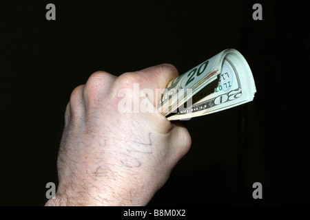 Caucasian Male main gauche serrant tas de USA vingt piastres avec le mot "oil" écrit sur la main. Banque D'Images