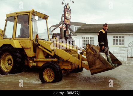 Towyn, galles, Février 1990 : vents d'ouragan cause la digue à Towyn à briser, inondant la ville côtière du nord du Pays de Galles. Un sauveteur rides par dans le godet d'un grand digger. Banque D'Images