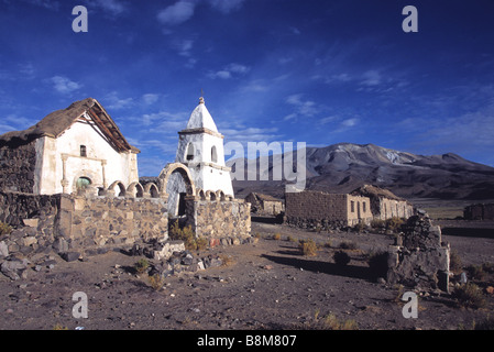 Adobe peint en blanc dans l'église du hameau abandonné de Caraguano, volcan Isluga en arrière-plan, le Parc National Isluga, Chili Banque D'Images