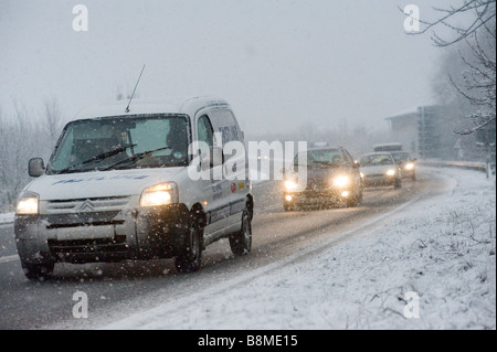 Van et voitures roulant lentement sur une route enneigée en hiver en Angleterre Banque D'Images