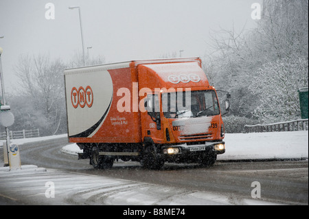 La conduite d'un camion de livraison TNT à travers la neige et la glace pour faire des livraisons sur une journée l'hiver en Angleterre Banque D'Images