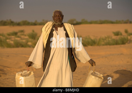 Abdeluahab watercans homme nommé apportant dans Banganarti près de Old Dongola région au Nil Nubie Soudan Banque D'Images