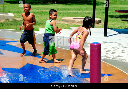 Trois enfants de diverses origines ethniques jouent dans un parc aquatique d'Oklahoma City, Oklahoma, États-Unis. Banque D'Images