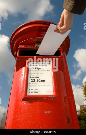 Une lettre est postée d'un rouge lumineux Royal Mail post box dans le Worcestershire en Angleterre Banque D'Images