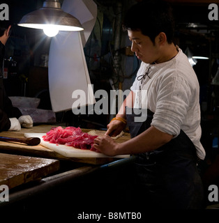 Marché de poissons worker cutting up pour sushi et sashimi de thon au marché central de vente en gros de la ville de Tokyo Tsukiji Fish Market Banque D'Images