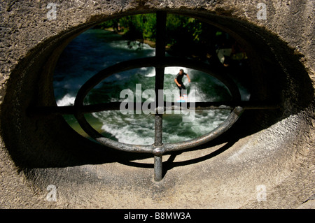 À travers l'orifice du pont à un internaute équitation une onde stationnaire sur l'Allemagne Bavière Munich Eisbach river Banque D'Images