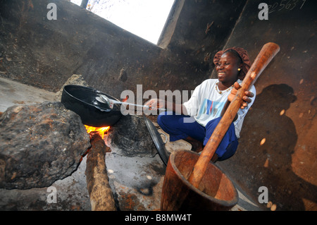 Femme la cuisson sur un feu ouvert dans son village rural de base cuisine, la Gambie, Afrique de l'Ouest Banque D'Images