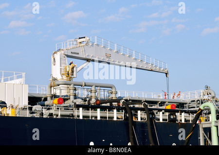 Une exploitation des travailleurs [flexible hydraulique grue de manutention] sur le pont d'un 'big rig' avec des tuyaux et flexibles visible sur [ciel bleu] Banque D'Images