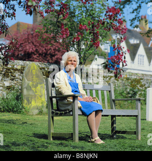 Femme âgée assise sur banc de parc en cimetière Banque D'Images