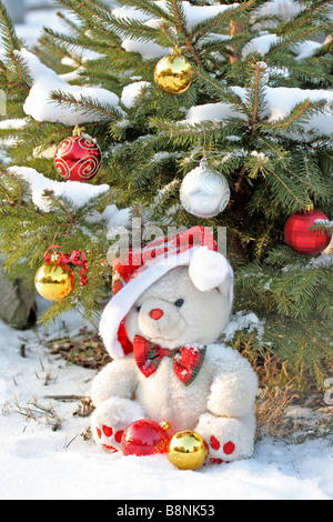 Fatso Bear se trouve sous l'arbre de Noël en plein air dans la neige Banque D'Images