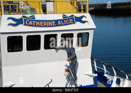 Man painting bateau de pêche. Le port de Howth, Co Dublin, Irlande. Banque D'Images