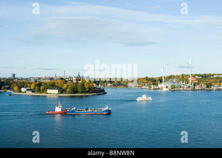 La Suède, Stockholm, le lac Malaren, tugboat pushing barge, ville en arrière-plan Banque D'Images