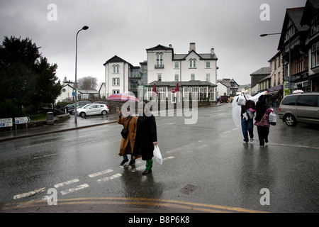 Les touristes asiatiques dans la pluie en Bowness on Windermere avec le Royal & Costa, dans l'arrière-plan Banque D'Images