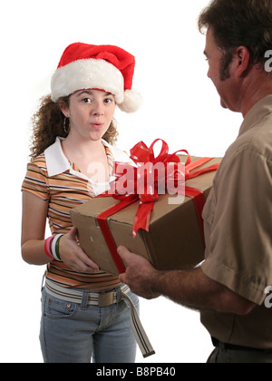 Une surprise girl in a santa hat recevoir un cadeau de Noël d'un homme isolé de livraison Banque D'Images