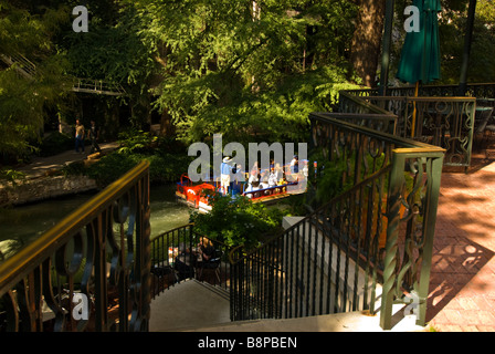 Promenade de la rivière San Antonio Riverwalk au-dessus de bateau d'excursion avec les passagers passe rangée d'escaliers menant à rivière arbres verts Banque D'Images