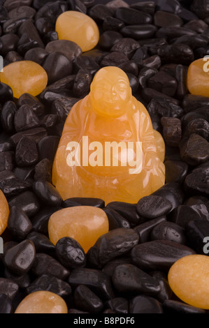 Sculpture Bouddha Calcite d'or sur noir riverstones Banque D'Images